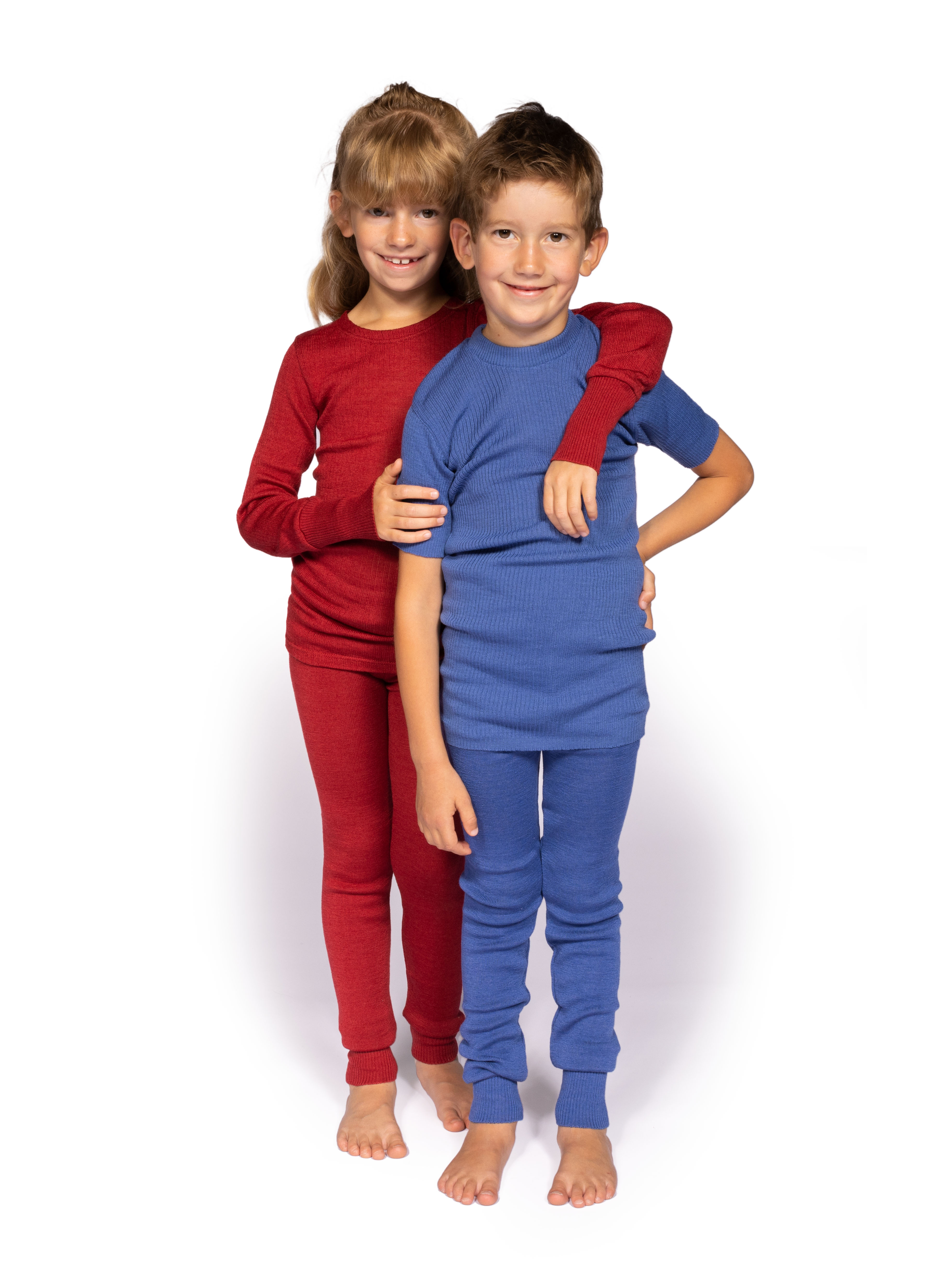 Kinder in bunter Thermounterwäsche Zwei Kinder in roter und blauer Thermounterwäsche umarmen sich lächelnd
