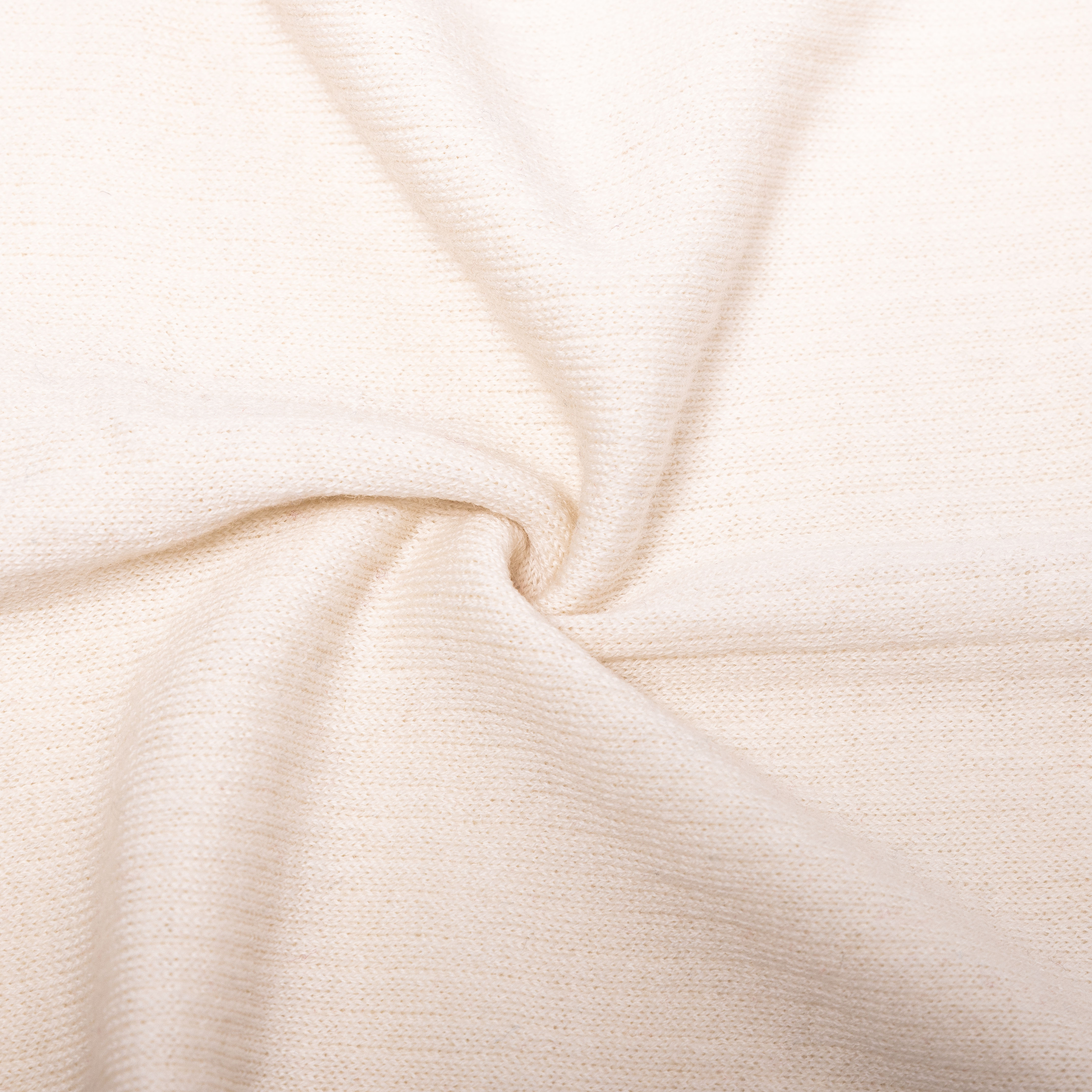 Weicher cremefarbener Strickstoff für Bekleidung und Dekoration Nahaufnahme eines weichen cremefarbenen Strickstoffs in Falten gelegt