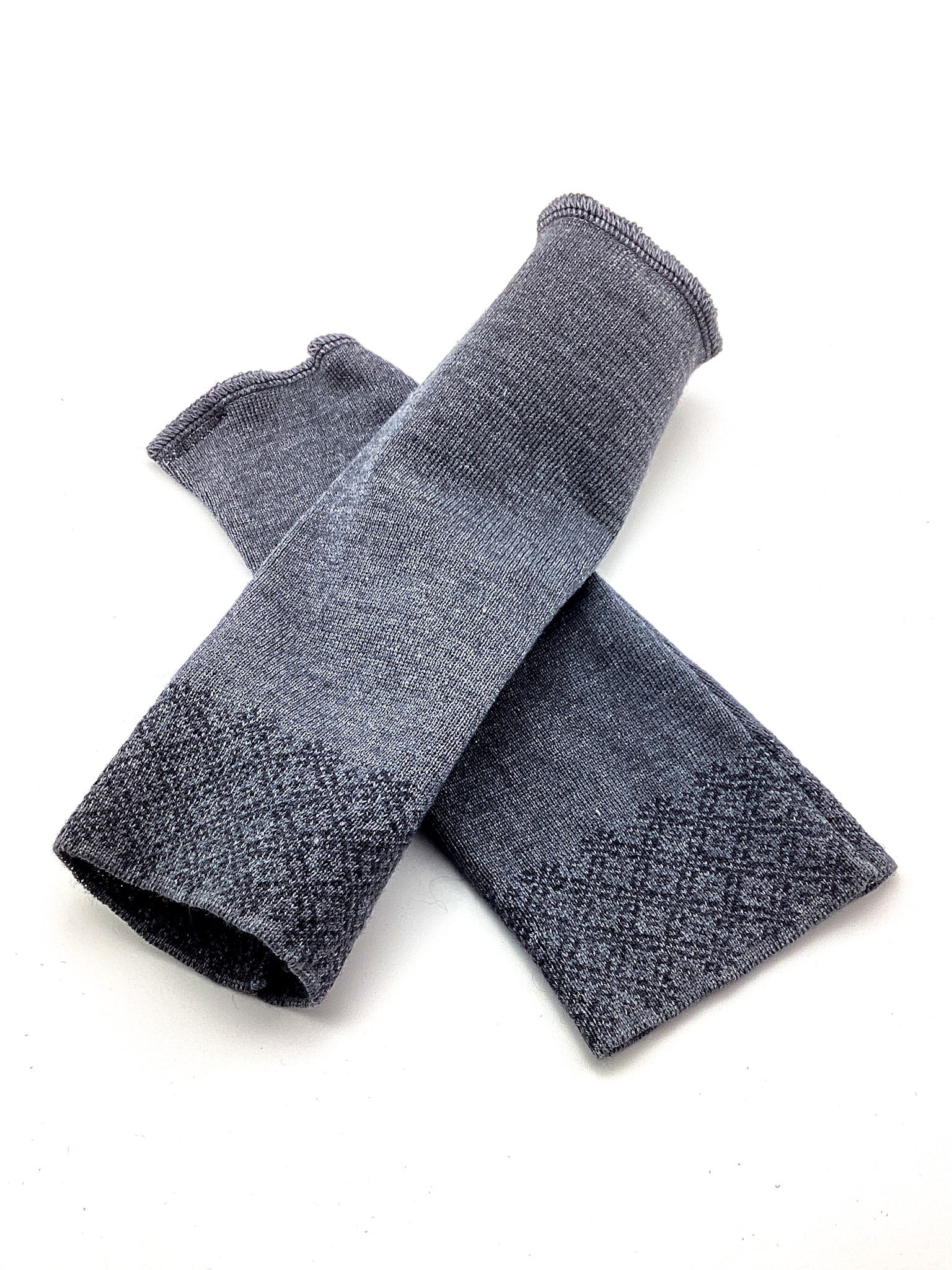 Graue Armwärmer mit Strickmuster Paar grauer Armwärmer mit dekorativem Strickmuster auf weißem Hintergrund