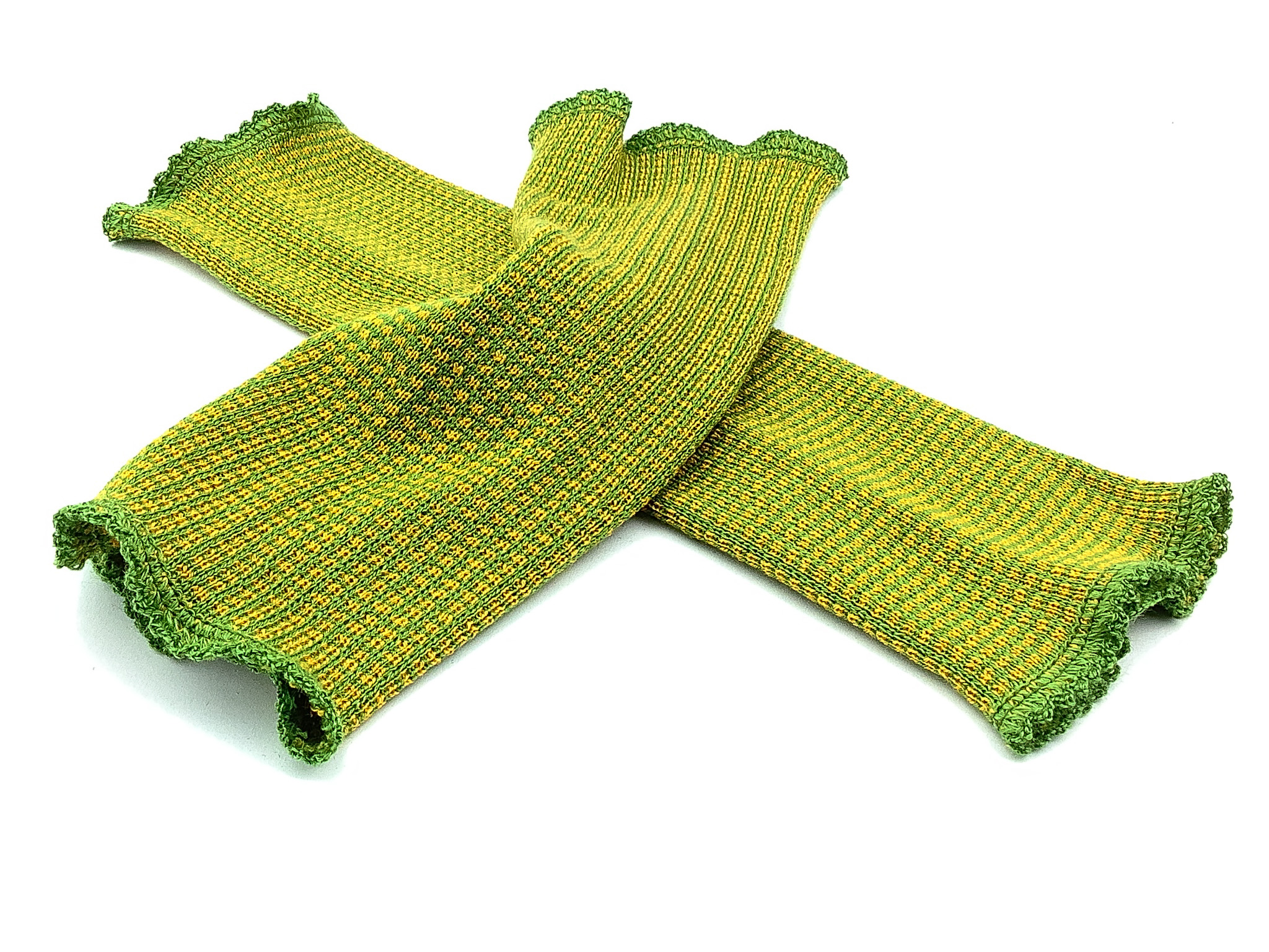 Handgestrickte grüne Pulswärmer mit Rüschenrand Ein Paar handgestrickte grüne Pulswärmer mit Rüschenrand in gelb-grüner Farbgebung vor weißem Hintergrund.