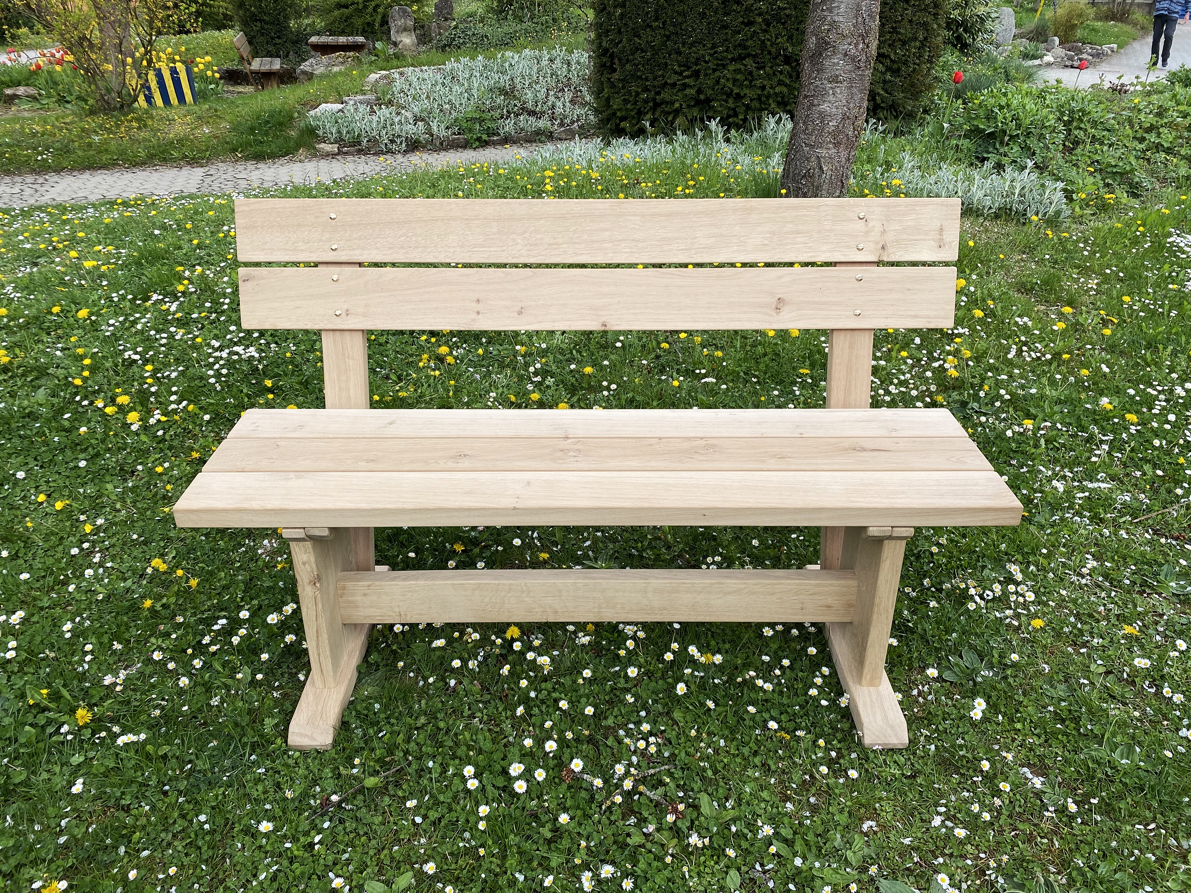 Naturholz-Gartenbank mit Rückenlehne auf blühender Wiese im Garten