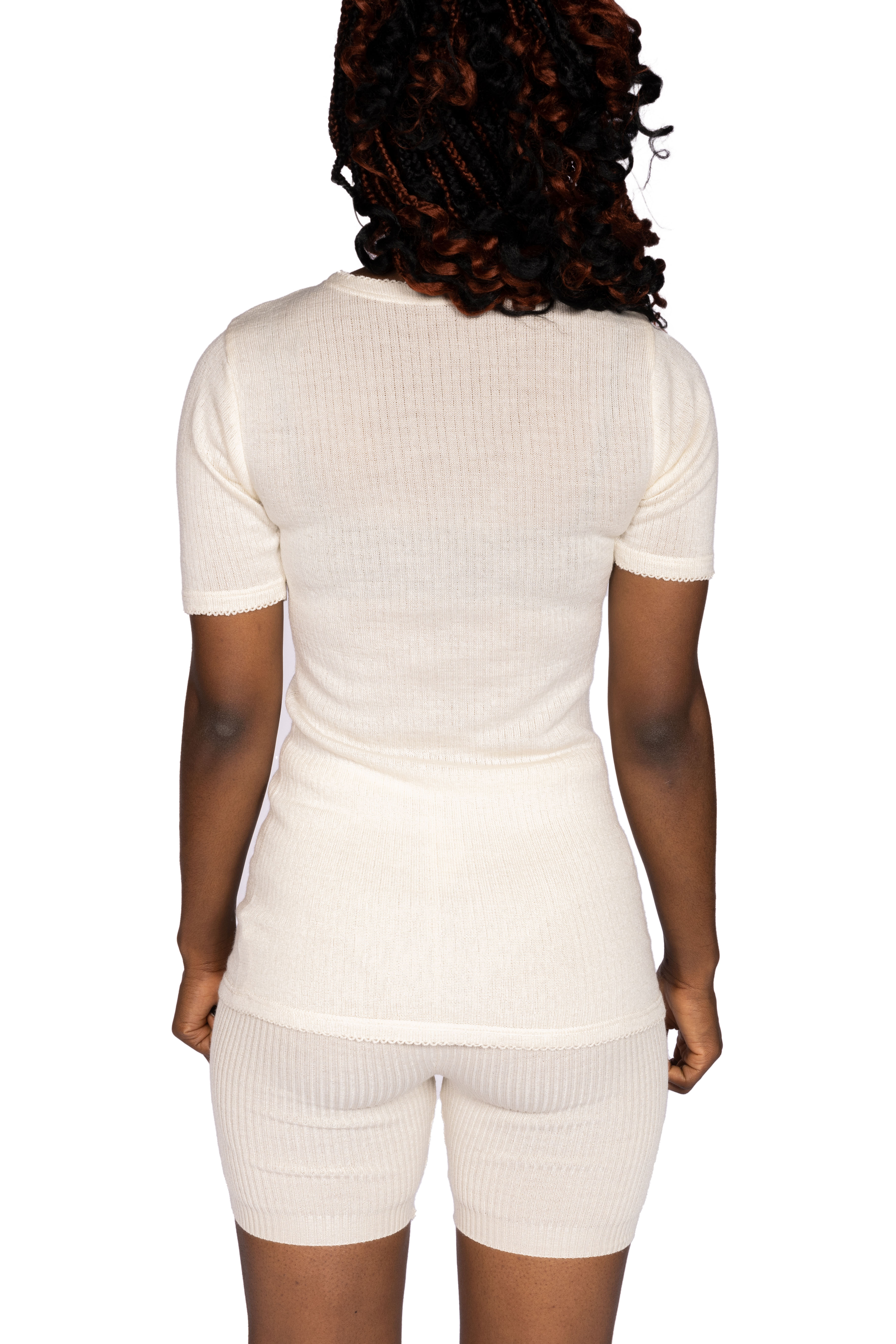 Rückansicht eines beige Damen-Pyjama-Sets Frau in einem beige Pyjama-Set aus T-Shirt und Shorts von hinten gesehen