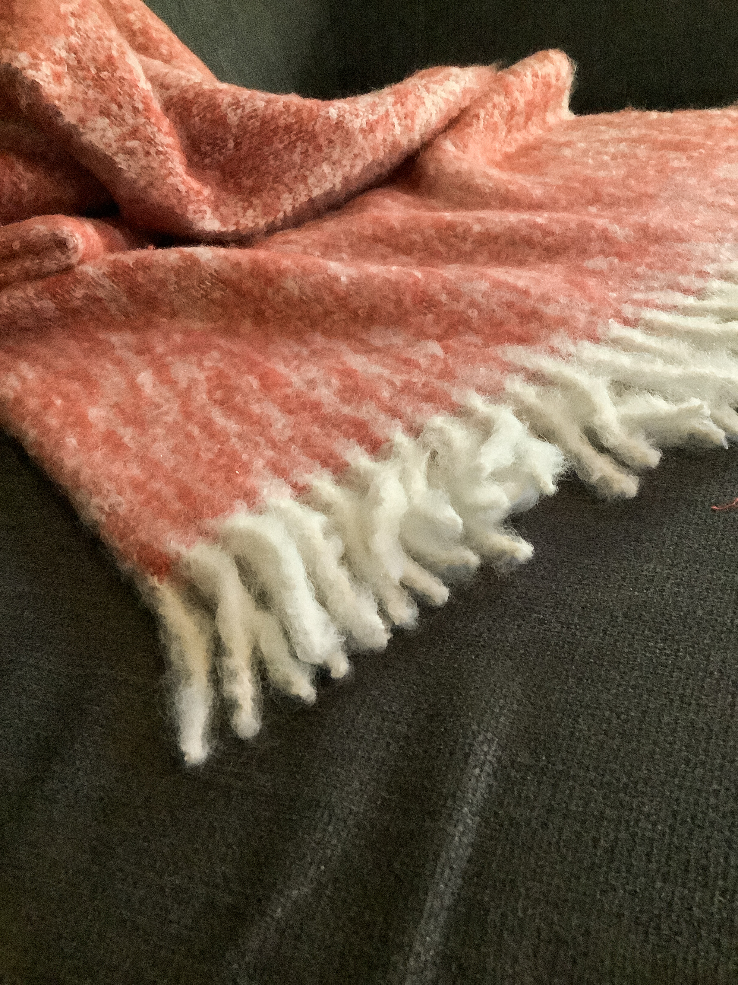 Weiche rot-weiße Kuscheldecke auf Sofa Flauschige rot-weiße Decke mit Fransen auf einem Sofa liegend