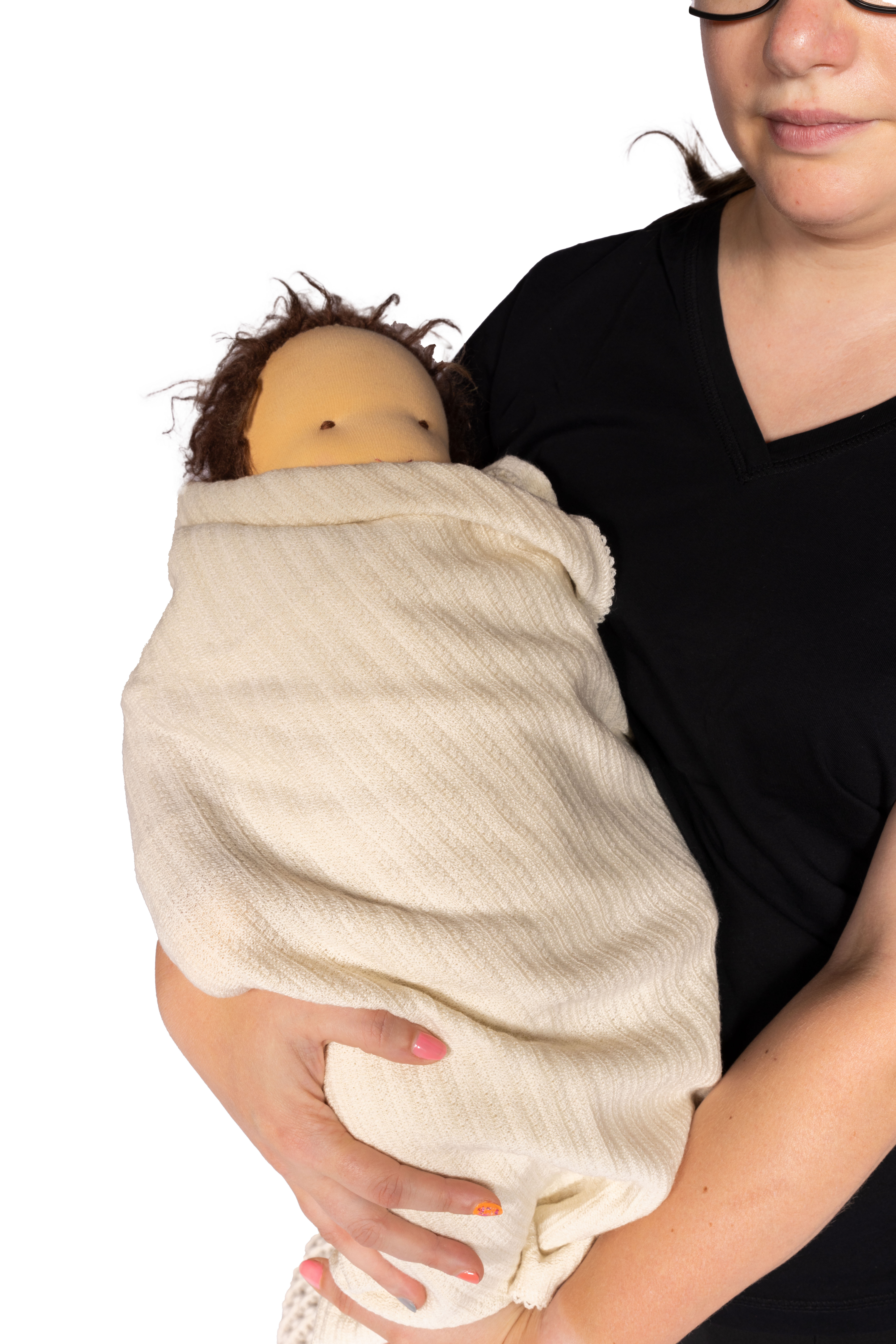 Person hält eine Puppe in einem Tuch Frau in schwarzem T-Shirt hält eine in ein cremefarbenes Tuch gewickelte Puppe