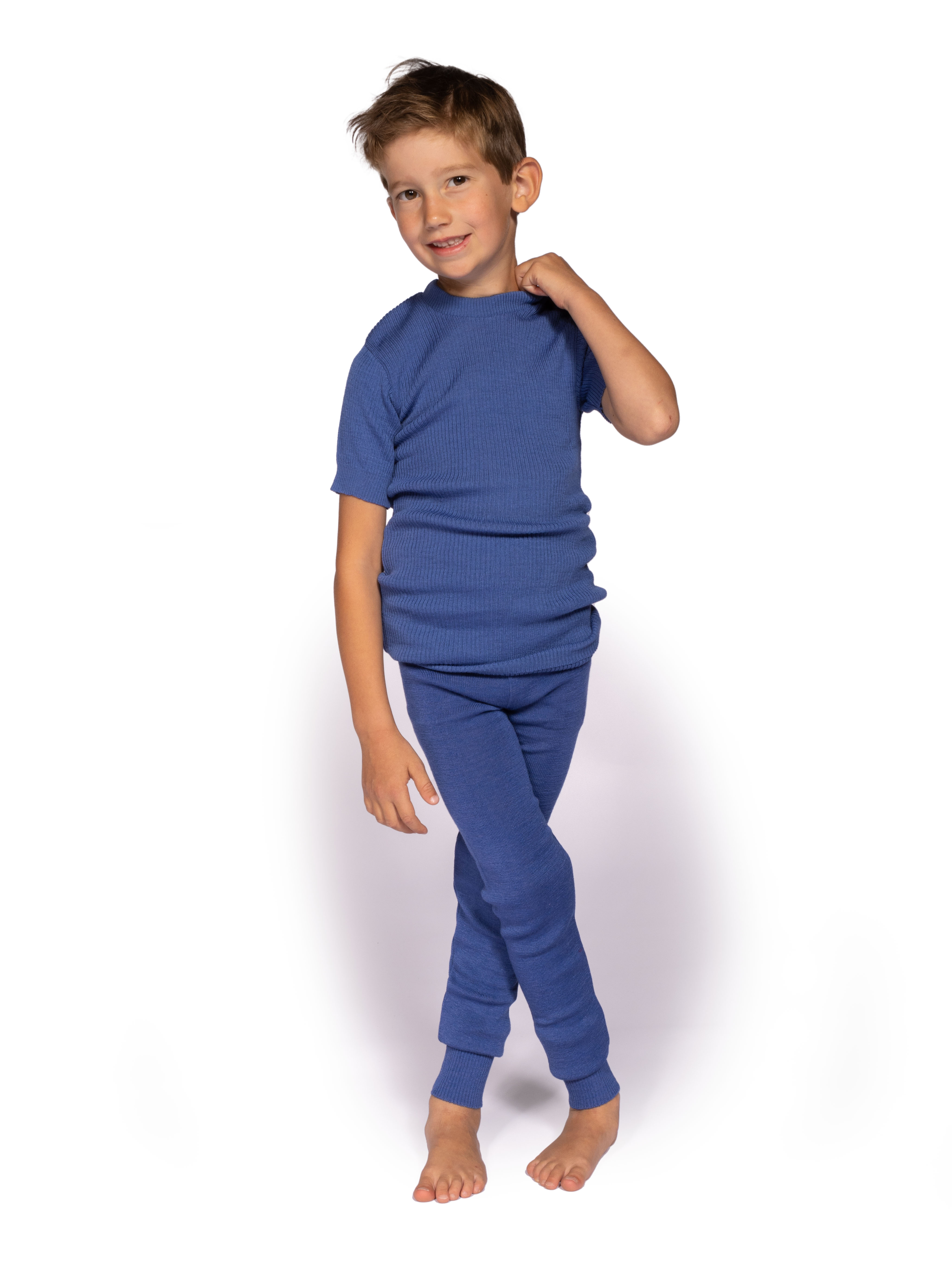 Junge in blauer Kinder-Pyjama-Set Lächelnder Junge trägt ein blaues Pyjama-Set für Kinder vor weißem Hintergrund
