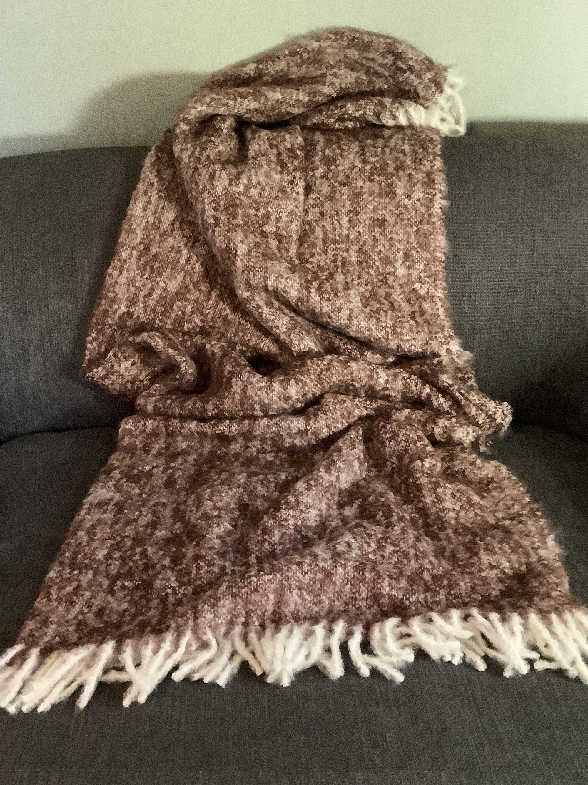 Weiche Kuscheldecke in Braun mit Fransen Braune Kuscheldecke mit Fransen auf einem grauen Sofa drapiert