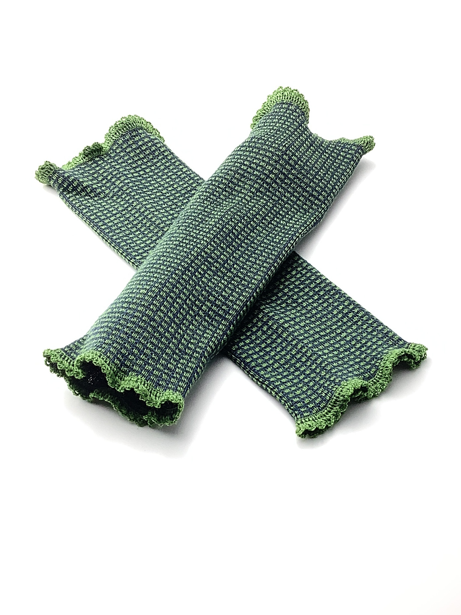 Grüne gestrickte Armstulpen mit Rüschenrand Zwei grüne gestrickte Armstulpen mit Rüschenrand auf weißem Hintergrund