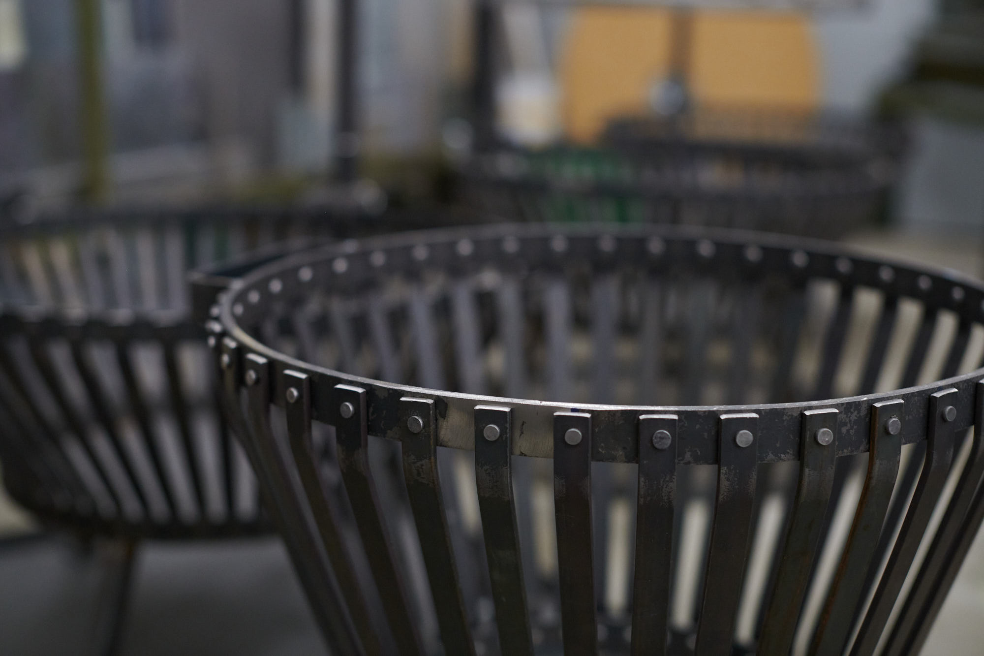 Nahaufnahme eines schwarzen Pflanzkübels aus Metall mit vertikalen Streben, ideal für moderne Außenanlagen und Stadtmöblierung