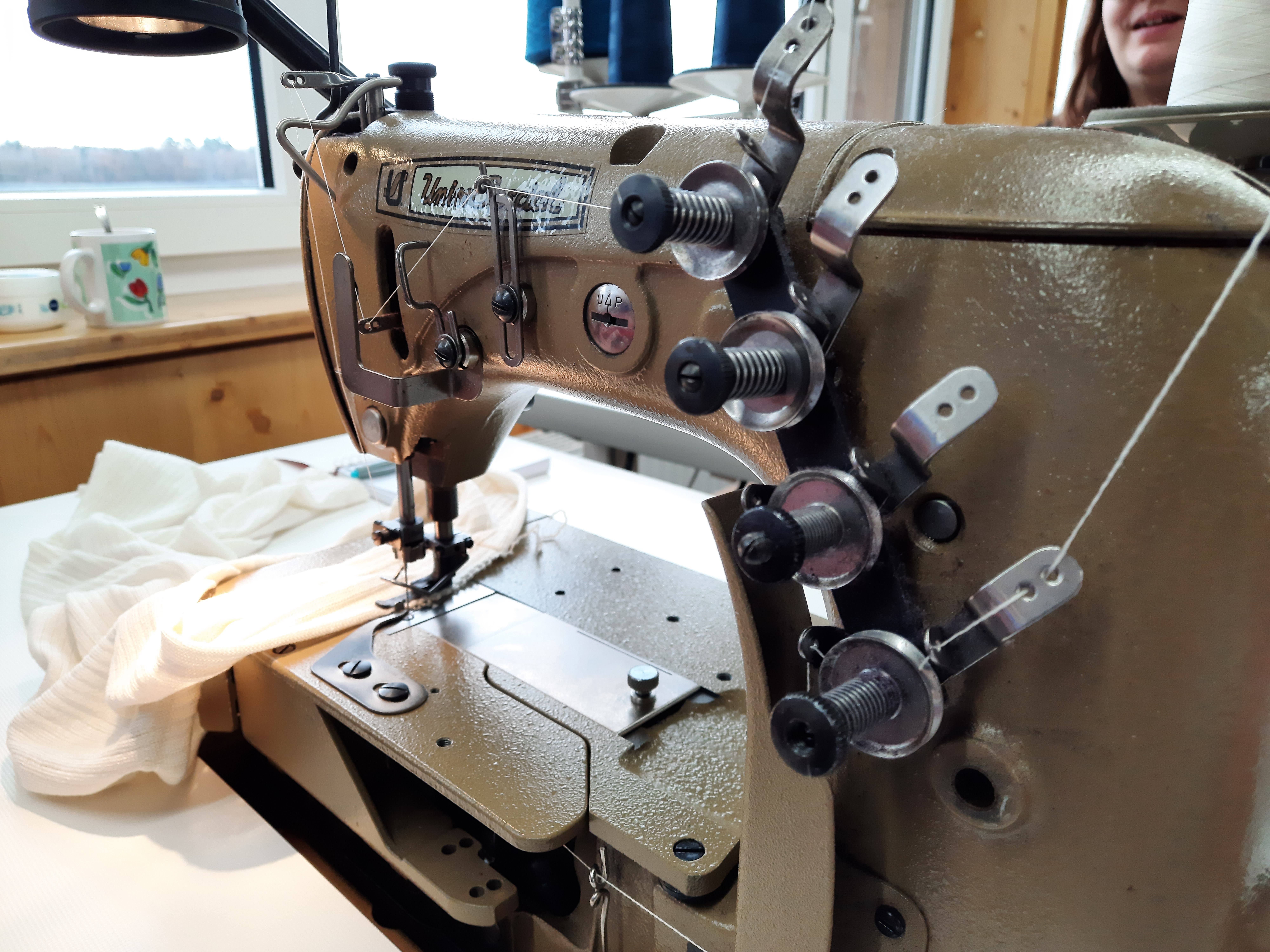 Industrielle Nähmaschine in einer Textilwerkstatt Große industrielle Nähmaschine mit Stoffstück in einer Werkstatt