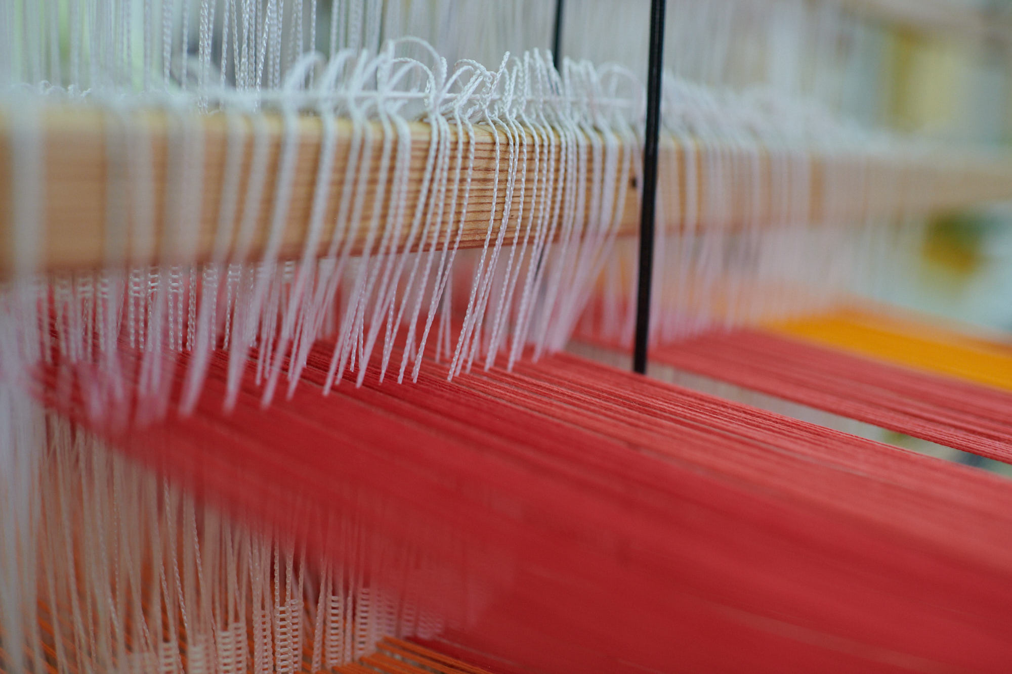 Webstuhl mit roten und weißen Fäden in Nahaufnahme Detailaufnahme eines Webstuhls mit roten und weißen Fäden, die entlang der Holzstreben gespannt sind