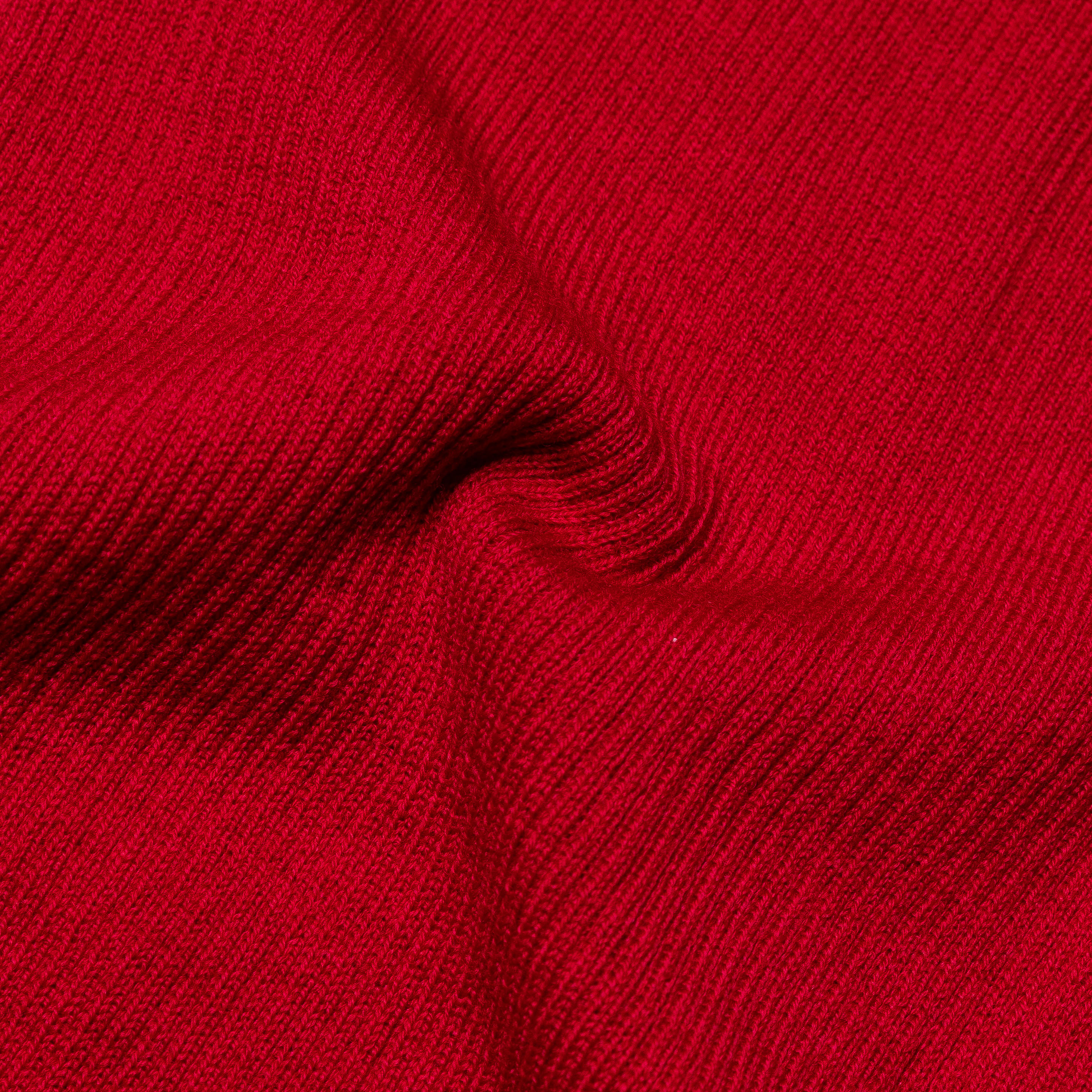 Detailaufnahme eines roten Strickstoffes Nahaufnahme eines roten, texturierten Strickstoffes mit weicher Struktur