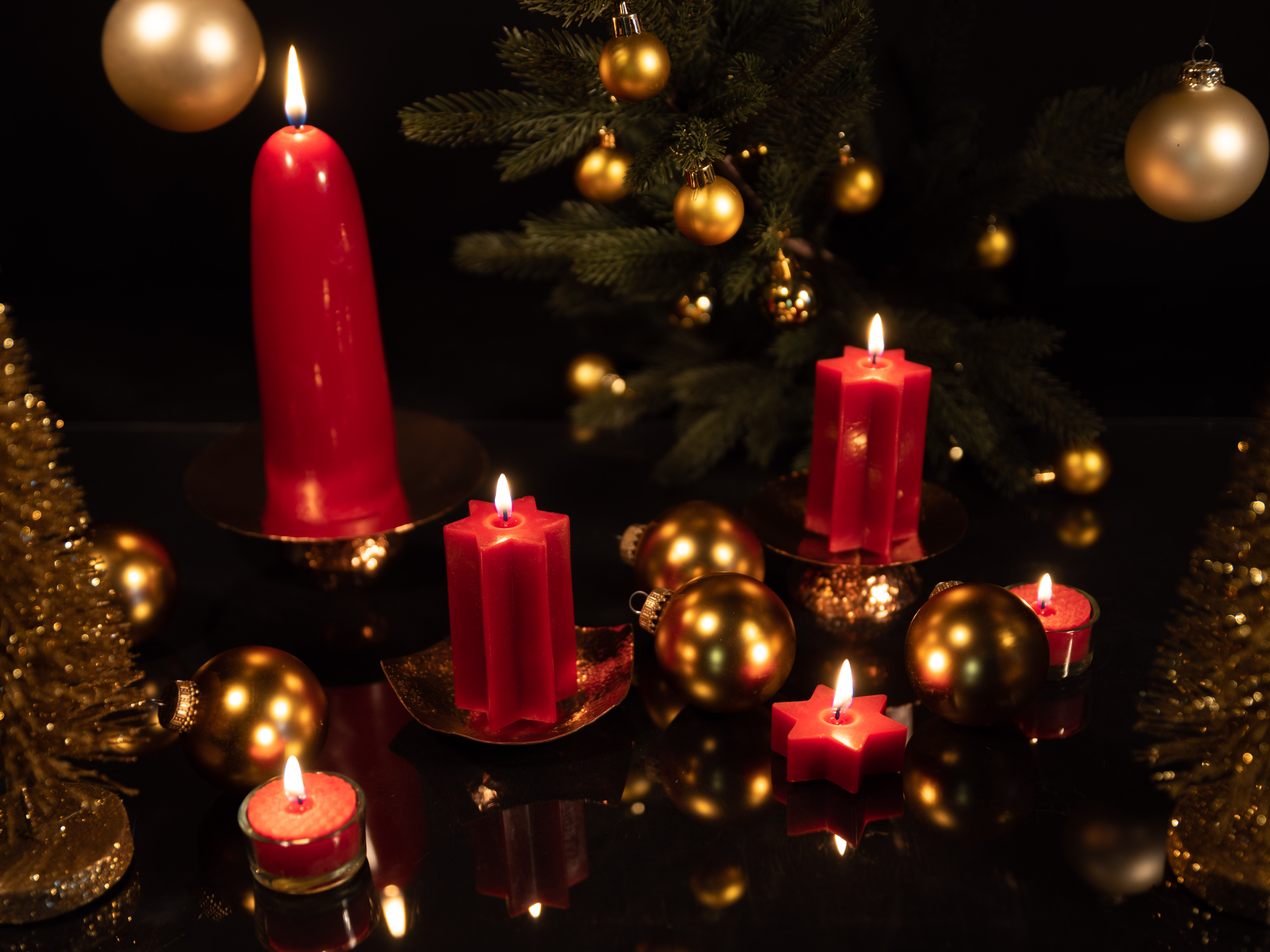 Festlicher Weihnachtsbild mit roten Kerzen und goldenen Kugeln Festliche Weihnachtsdekoration mit brennenden roten Kerzen, goldenen Kugeln und Tannenzweigen