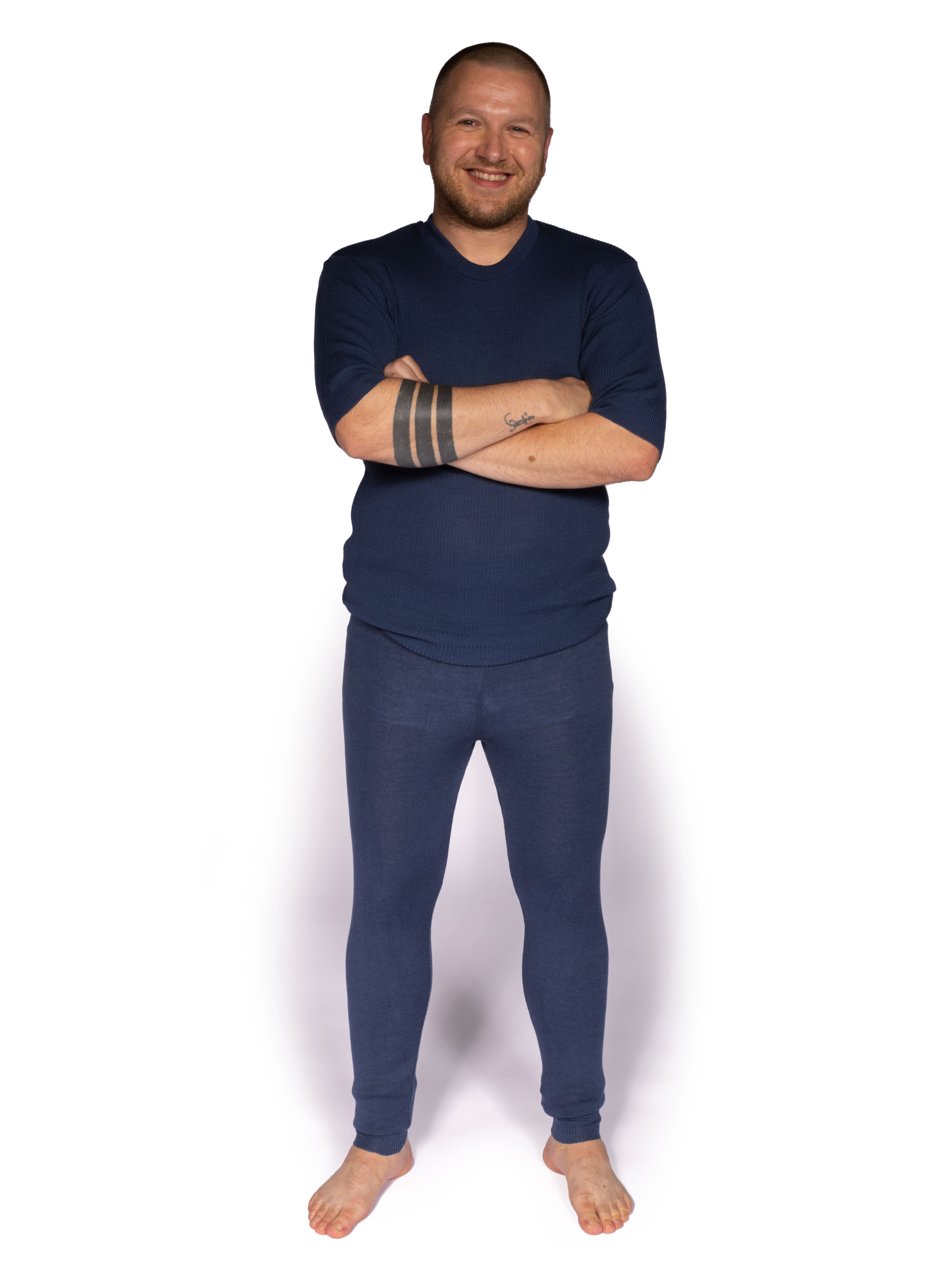Mann in blauer Thermounterwäsche für Komfort und Wärme Ein Mann in blauer Thermounterwäsche steht mit verschränkten Armen und lächelt, ideal für kaltes Wetter und Komfort.