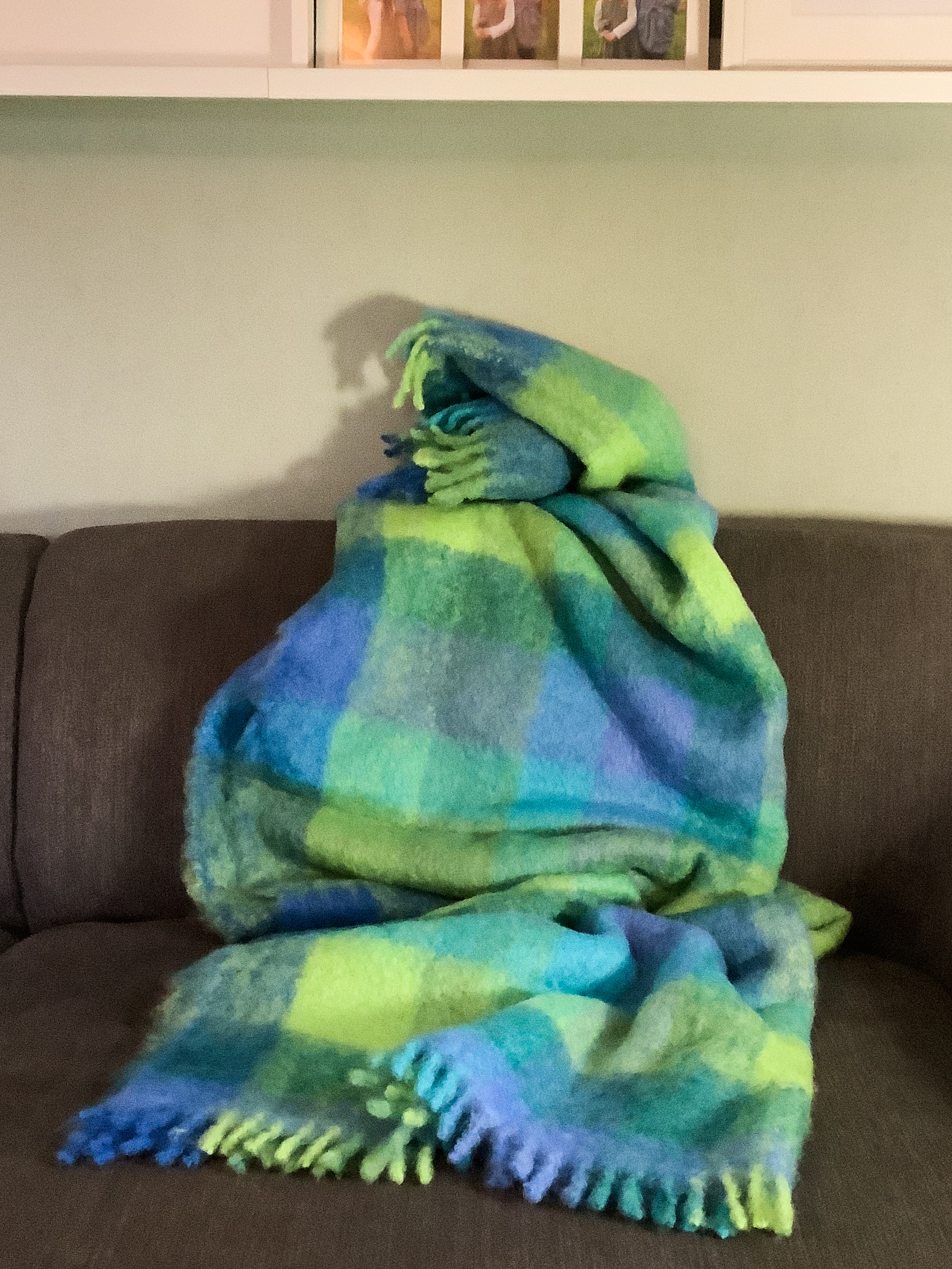 Weiche Decke in buntem Karomuster auf Sofa Bunte Decke mit Karomuster auf einem grauen Sofa platziert