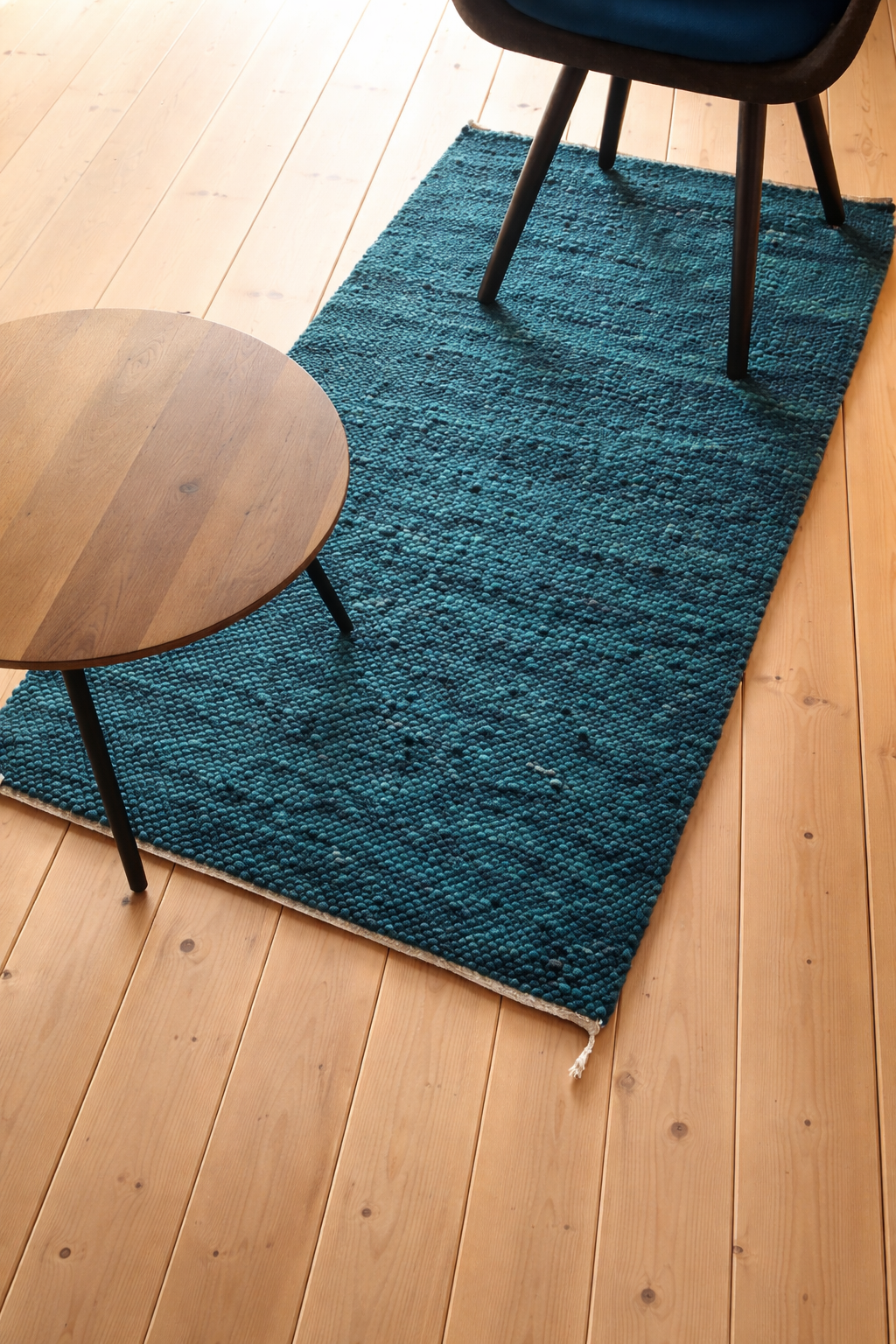 Türkisfarbener Läufer-Teppich auf hellem Holzboden, kombiniert mit rundem Beistelltisch und Stuhl im modernen Wohnbereich