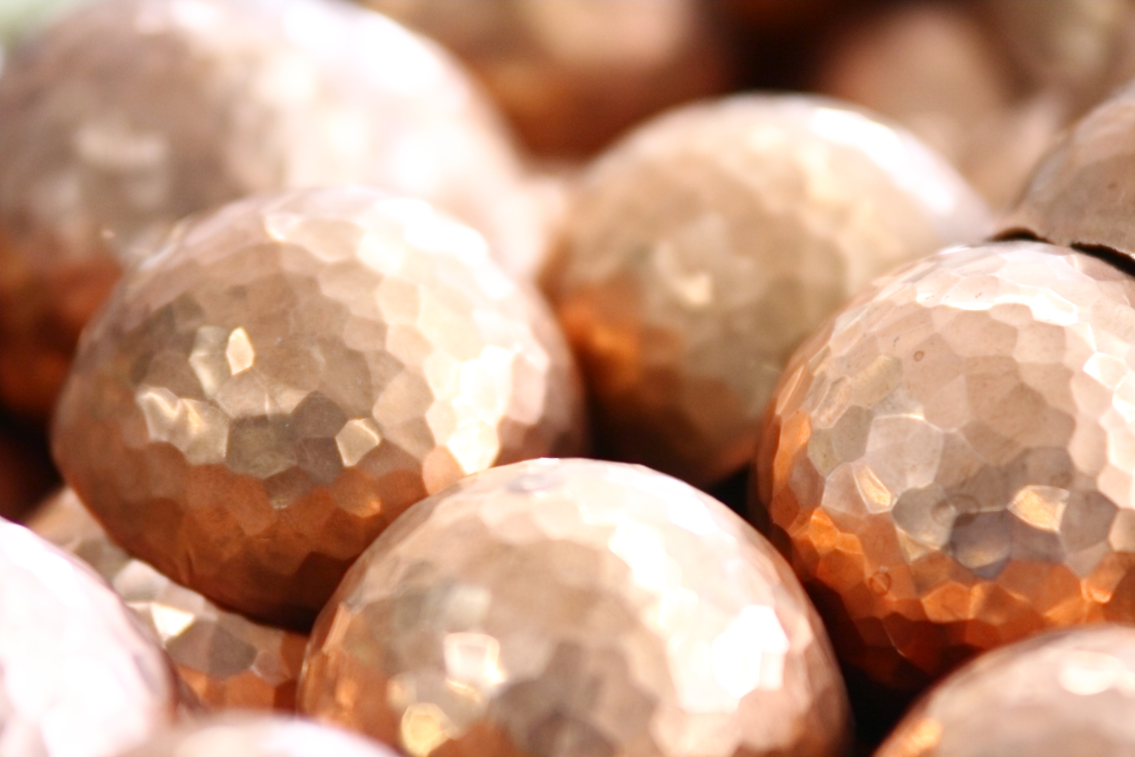 Nahaufnahme von glänzenden Kupferkugeln mit gehämmerter Oberfläche Mehrere glänzende und gehämmerte Kupferkugeln in Nahaufnahme