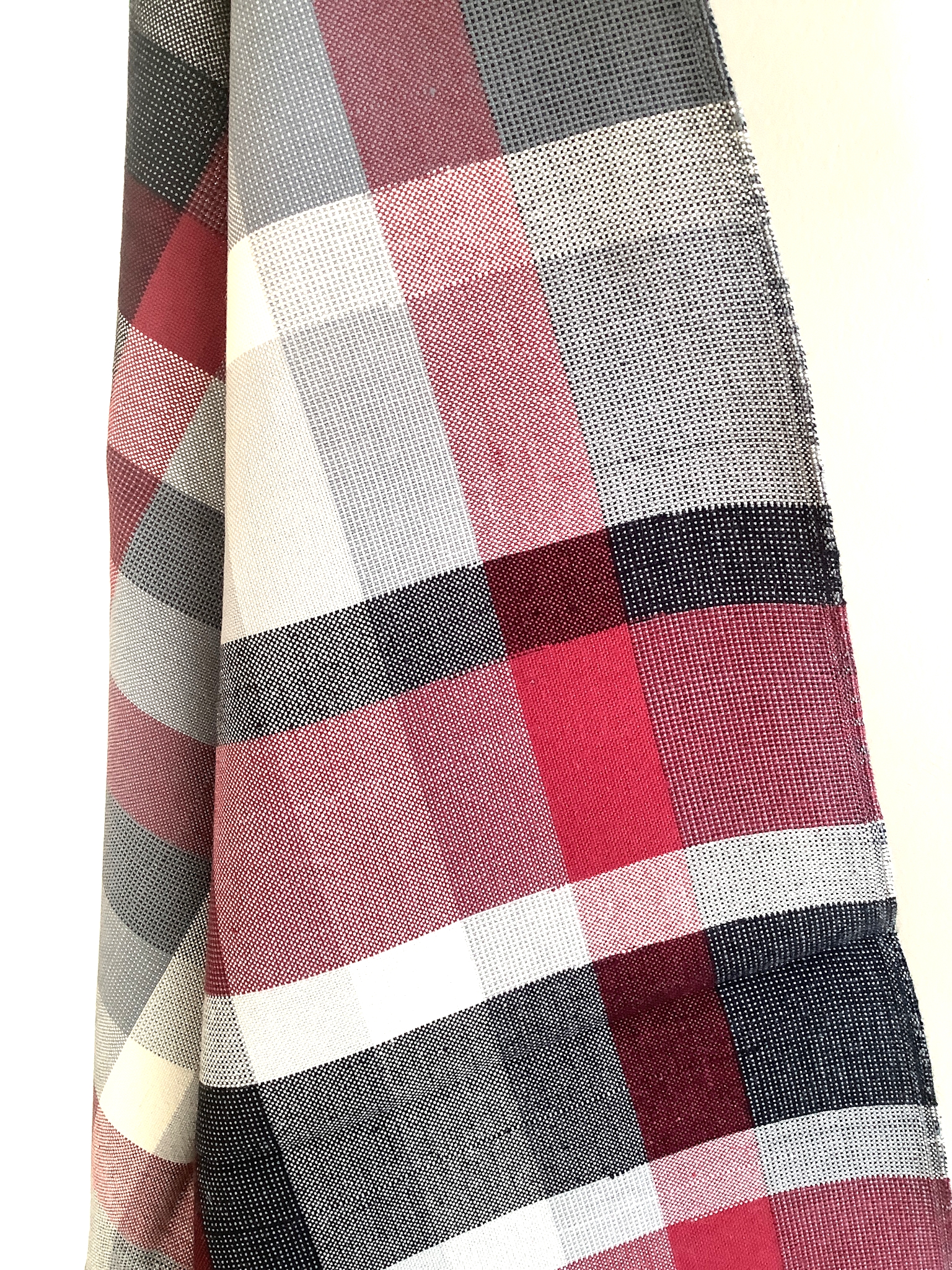 Nahaufnahme eines karierten Küchentuchs in Rot, Grau, Schwarz und Weiß aus fein gewebter Baumwolle, ideal als saugfähiges Geschirrtuch