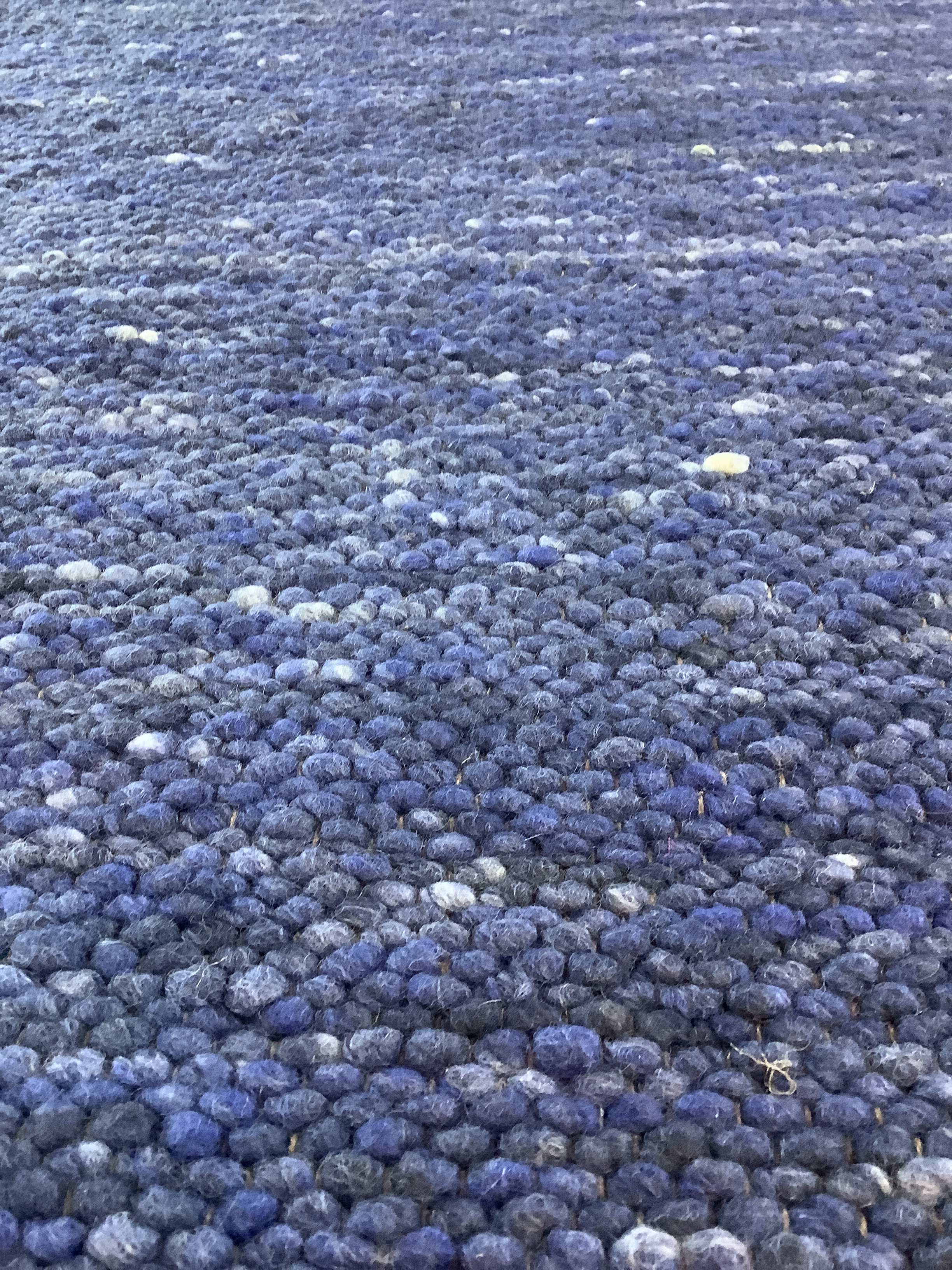 Detailansicht eines blauen handgewebten Wollteppichs mit dichter, strukturierter Knüpfoberfläche