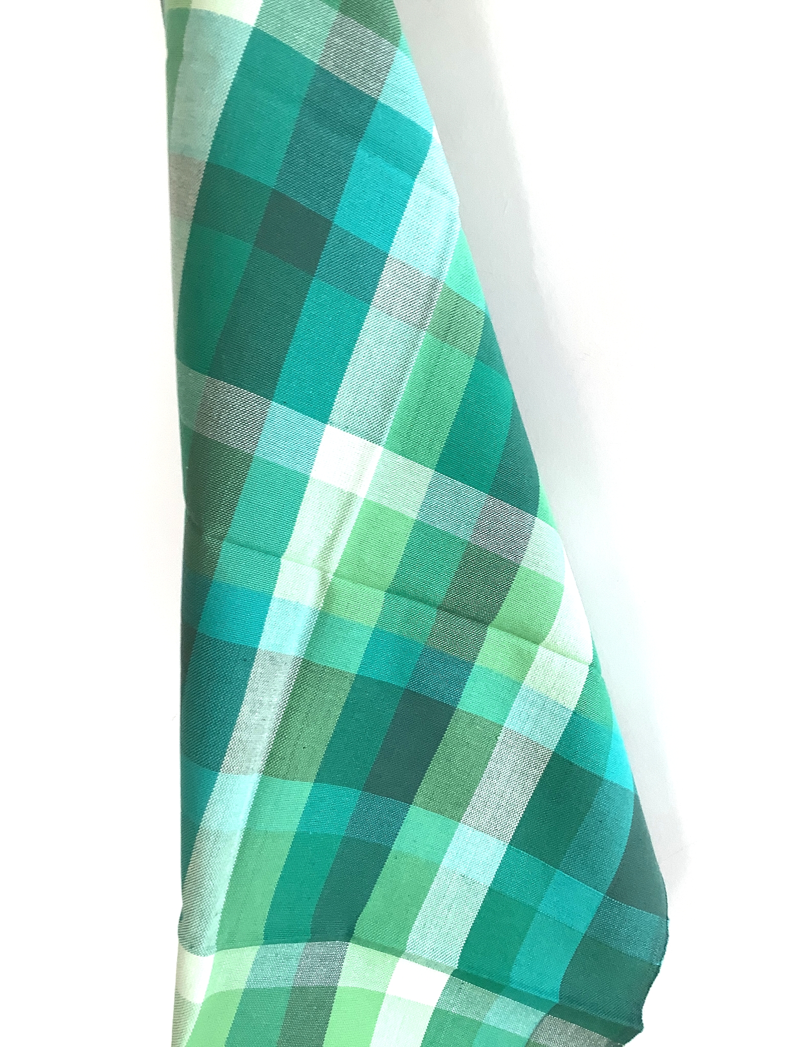Aufgehängtes Baumwoll-Geschirrtuch mit grün-türkisem Karomuster vor weißem Hintergrund