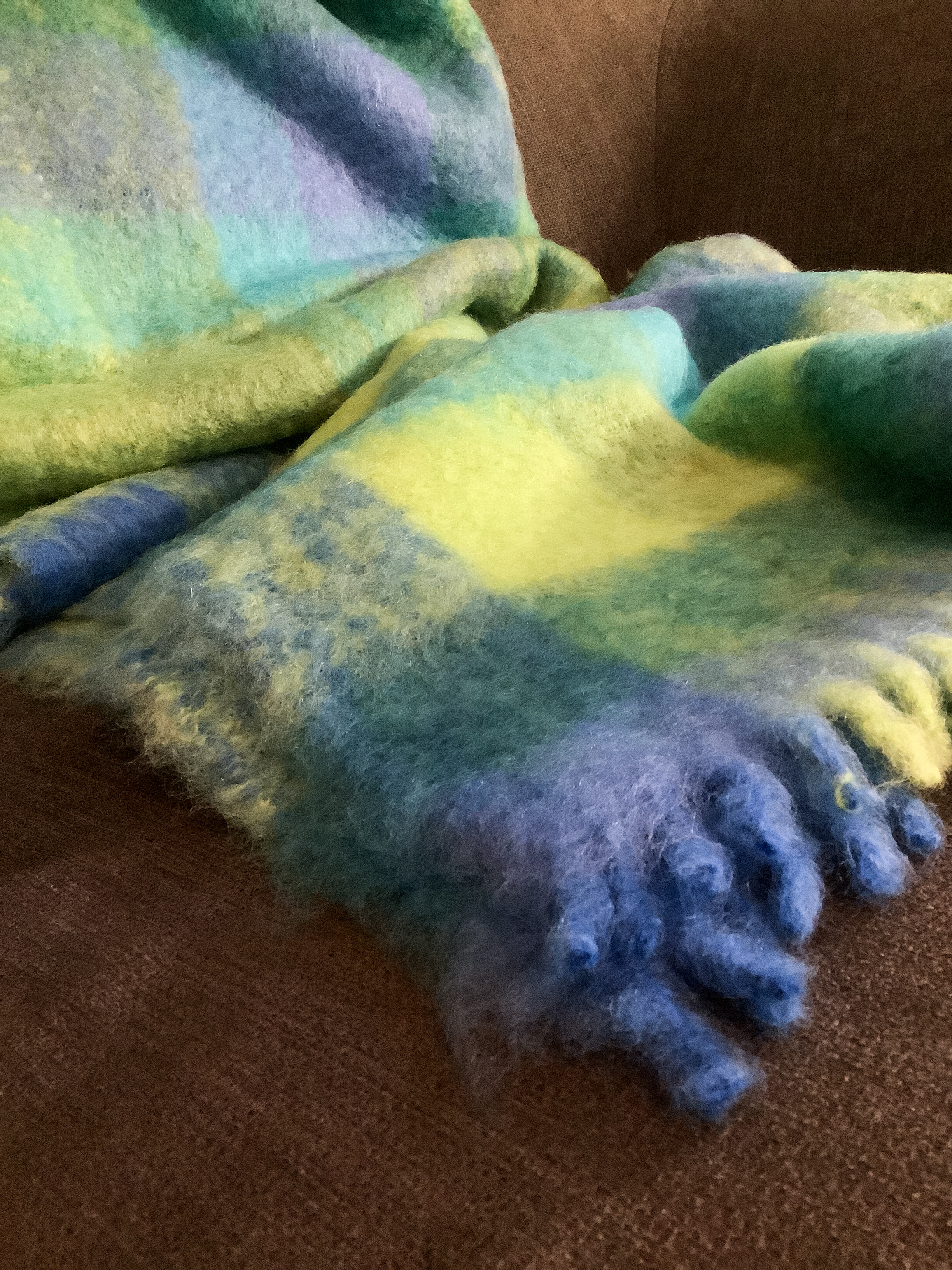 Kuschelige Decke in Blau- und Grüntönen auf einem Sofa Warme, weiche Decke in Blau- und Grüntönen liegt auf einem Sofa