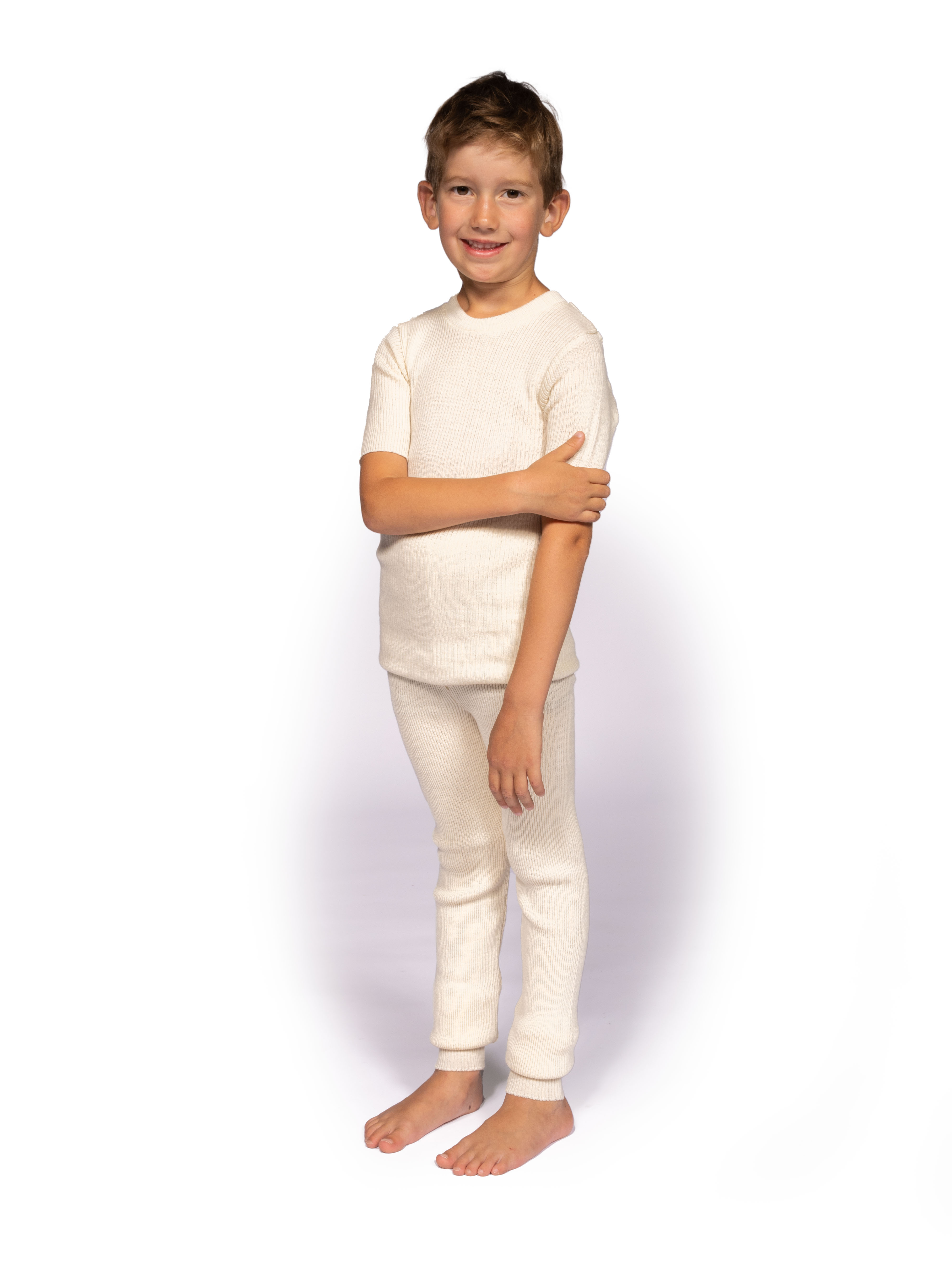 Junge in weißem Unterwäscheset steht vor weißem Hintergrund