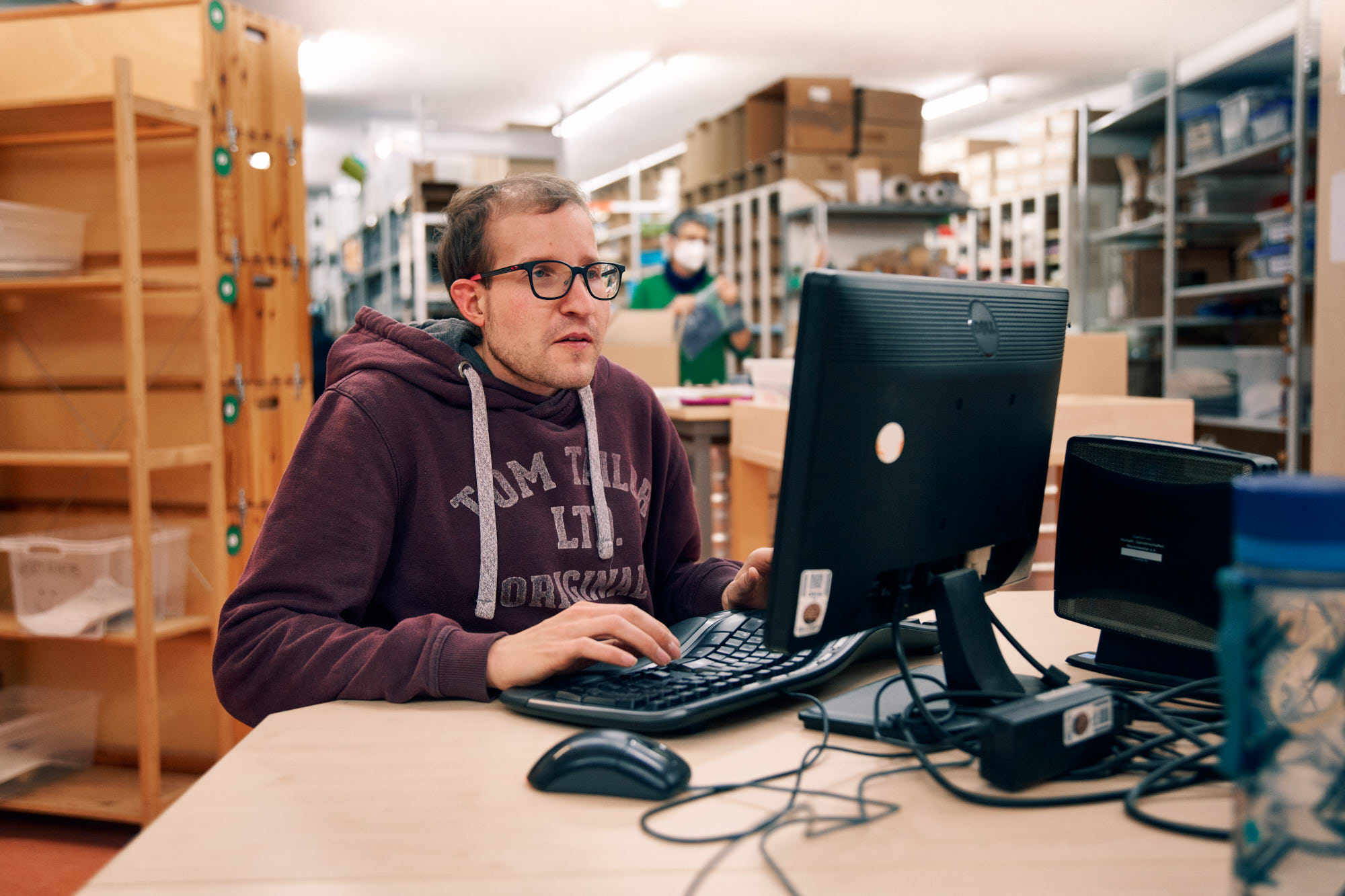 Mitarbeiter im Lager arbeitet am Computer Ein Mann sitzt im Lager vor einem Computer und arbeitet konzentriert