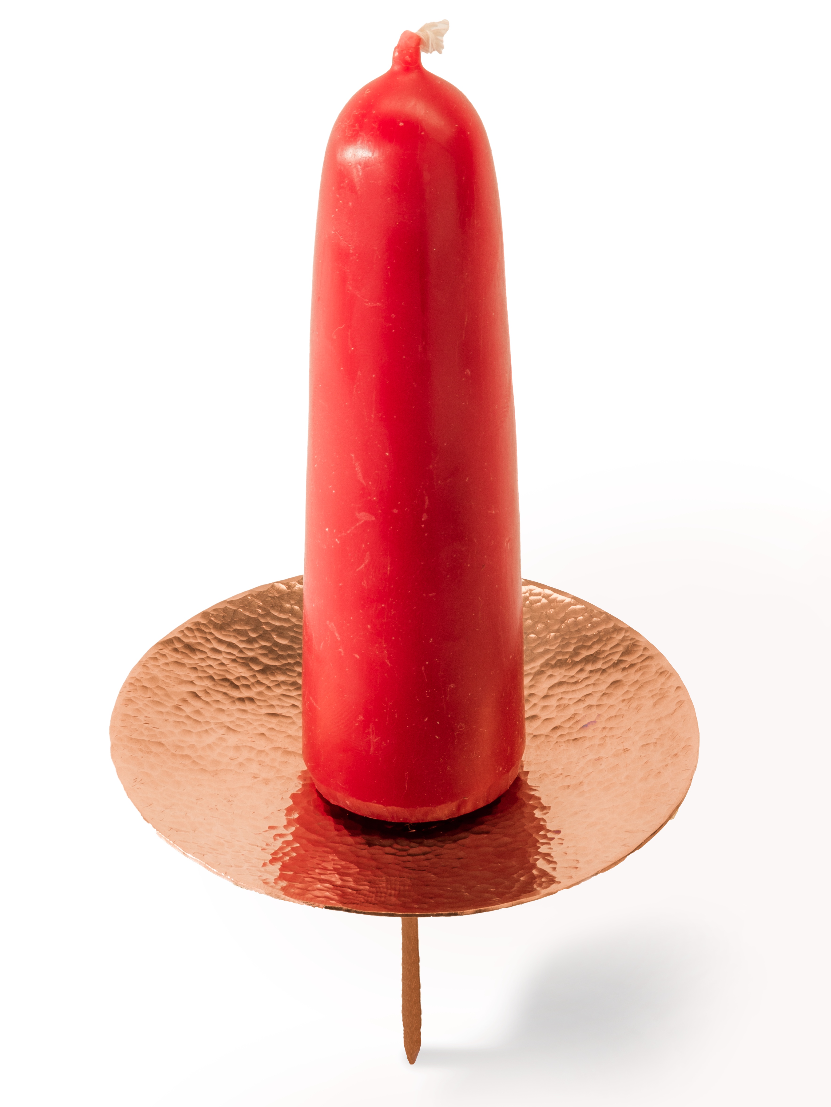 Rote Kerze auf Kupferteller Eine rote Kerze steht auf einem metallenen Kupferteller mit Dorn.